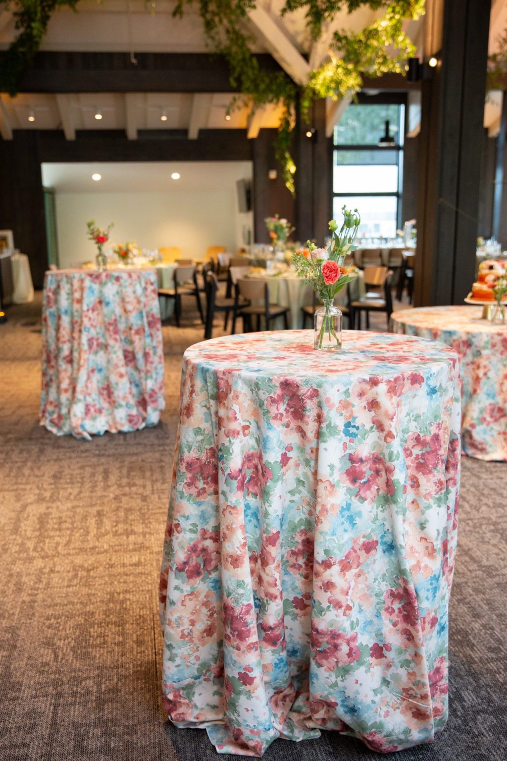 Haley and Sam's wedding at Buttermilk Mountain Lodge, Aspen: Cocktail tables in watercolor floral linens with bud vases