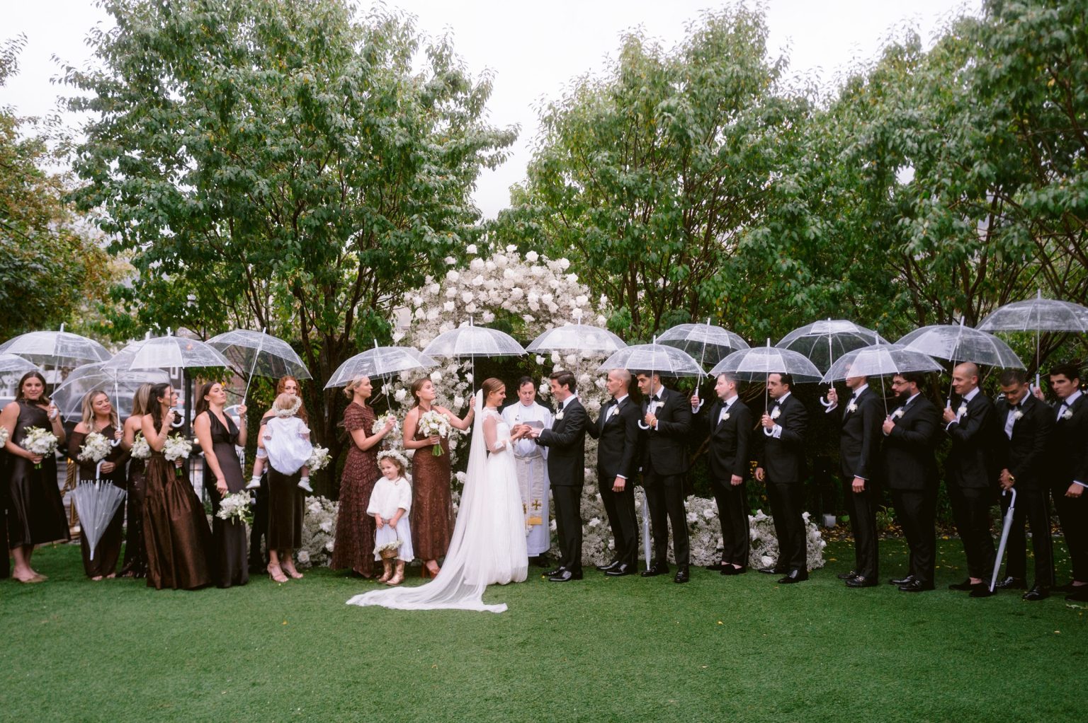 Addy & Nick's wedding at Hotel Jerome, Aspen: guests under clear umbrellas at the courtyard ceremony