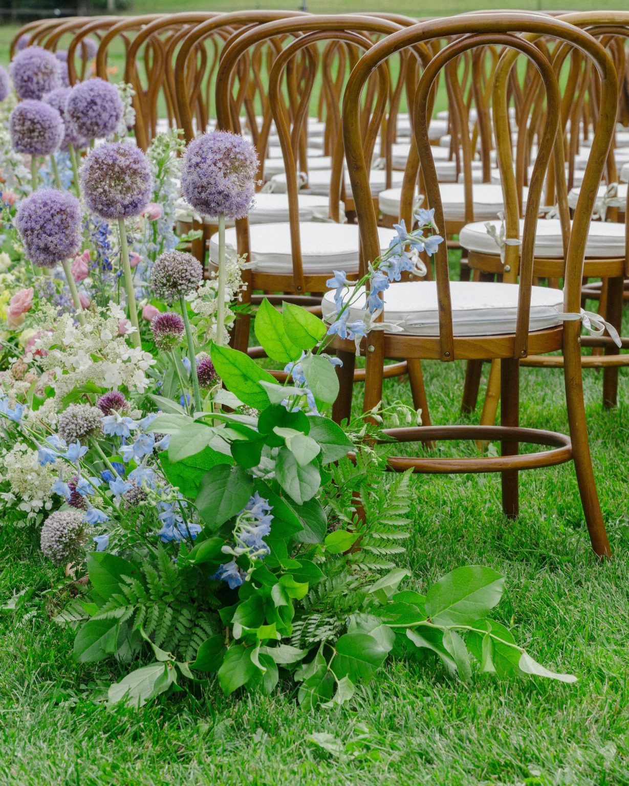 A wildflower wedding at T Lazy 7 Ranch, Aspen: allium and delphinium at the end of a row of bentwood chairs