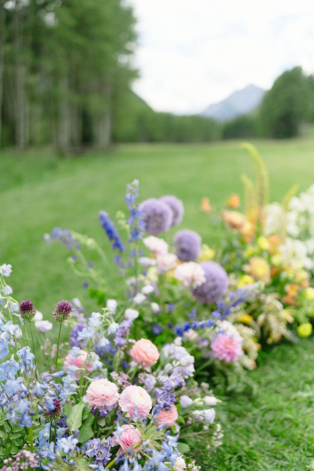 A wildflower wedding at T Lazy 7 Ranch, Aspen: a low aisle border of lavender, blush, and apricot blooms
