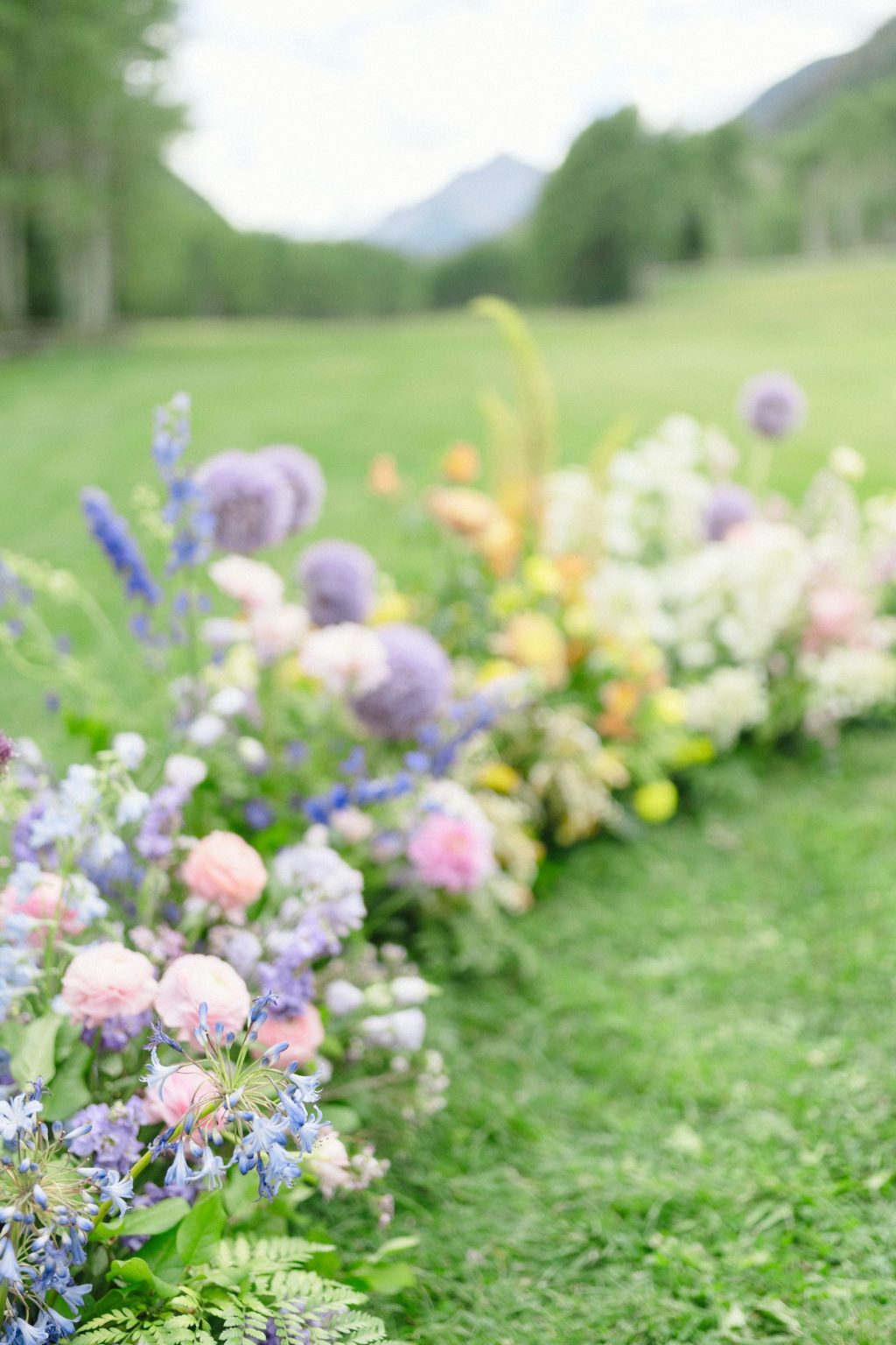 A wildflower wedding at T Lazy 7 Ranch, Aspen: meadow-style florals running along the ceremony aisle