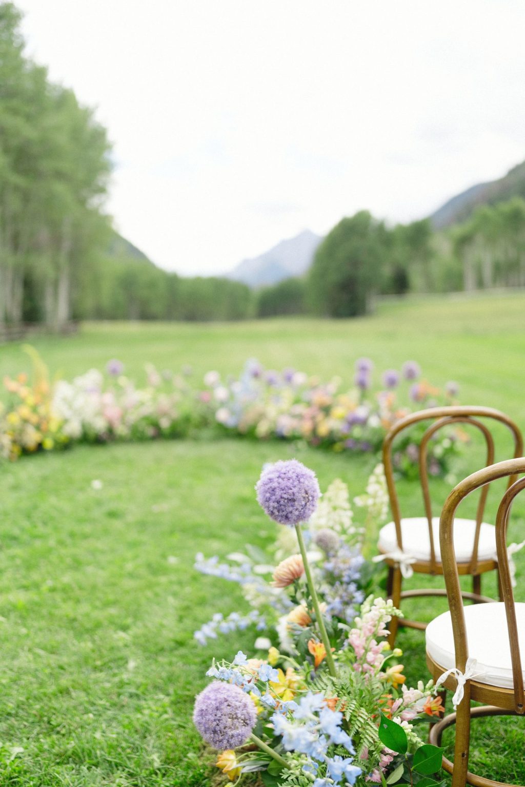 A wildflower wedding at T Lazy 7 Ranch, Aspen: the ceremony florals curving toward the aspens