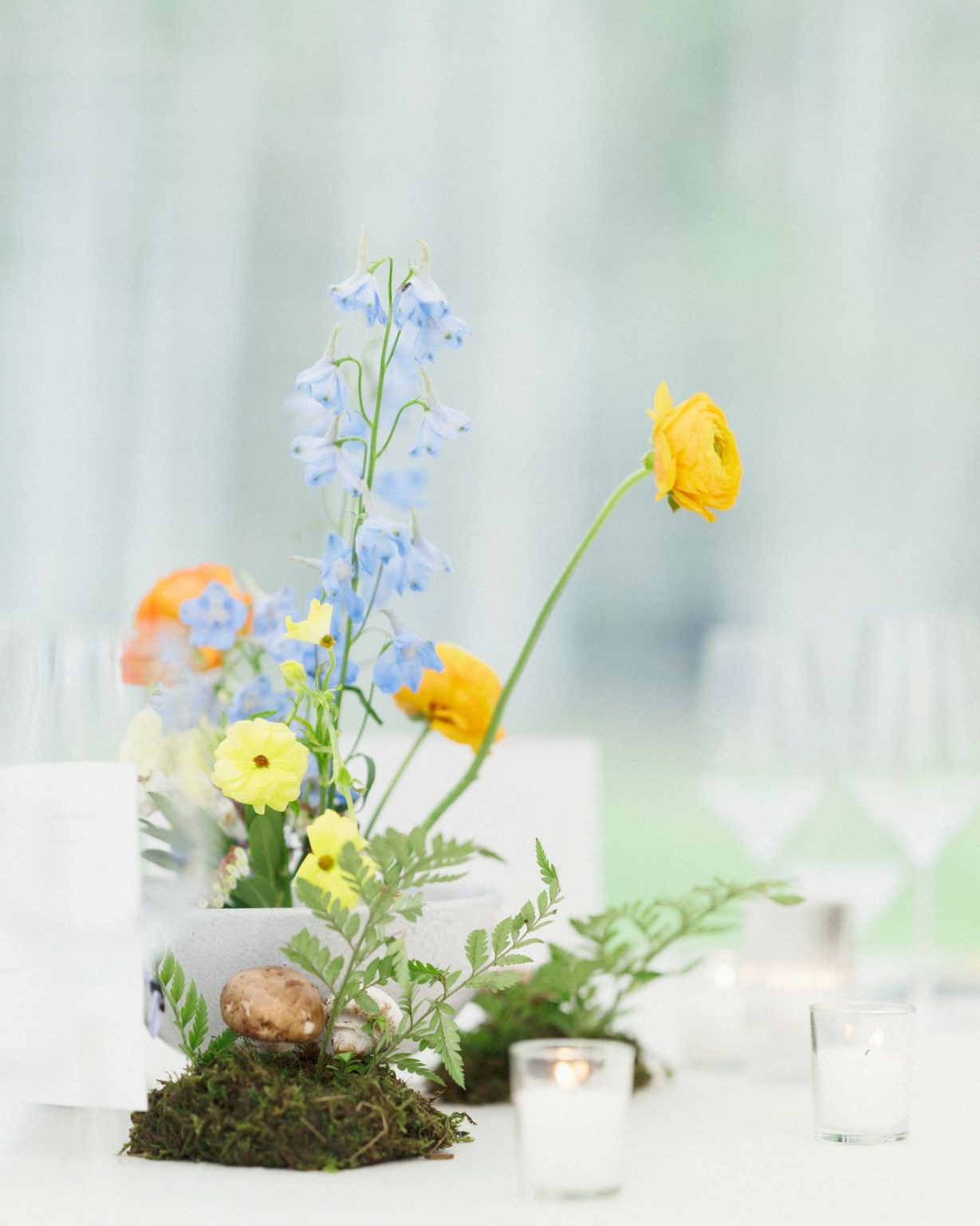 A wildflower wedding at T Lazy 7 Ranch, Aspen: poppies and delphinium in a low arrangement with moss and mushrooms