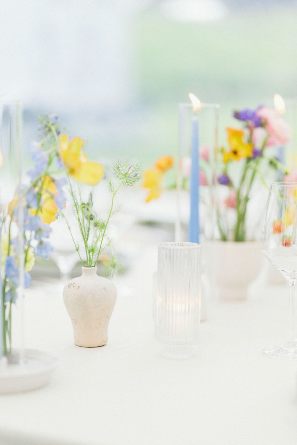 A wildflower wedding at T Lazy 7 Ranch, Aspen: butter-yellow blooms and pale blue tapers in ceramic bud vases
