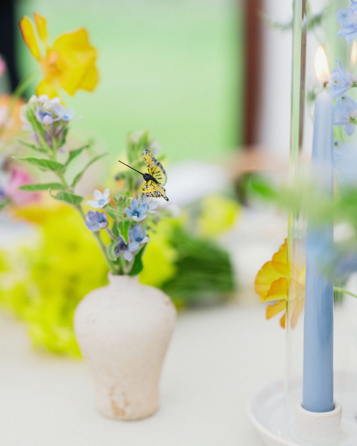 A wildflower wedding at T Lazy 7 Ranch, Aspen: a butterfly on a bud vase of yellow blooms